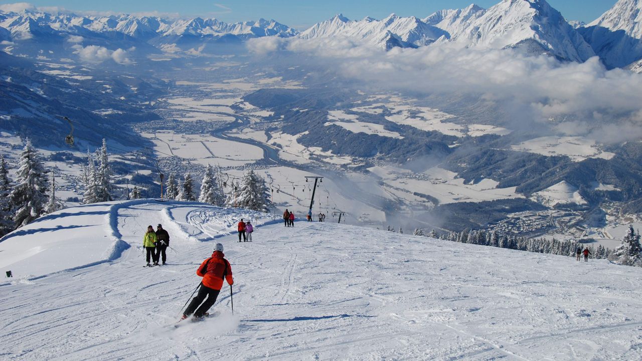 Burglift – Stans in Austria - a group of people skiing down a snow covered mountain.