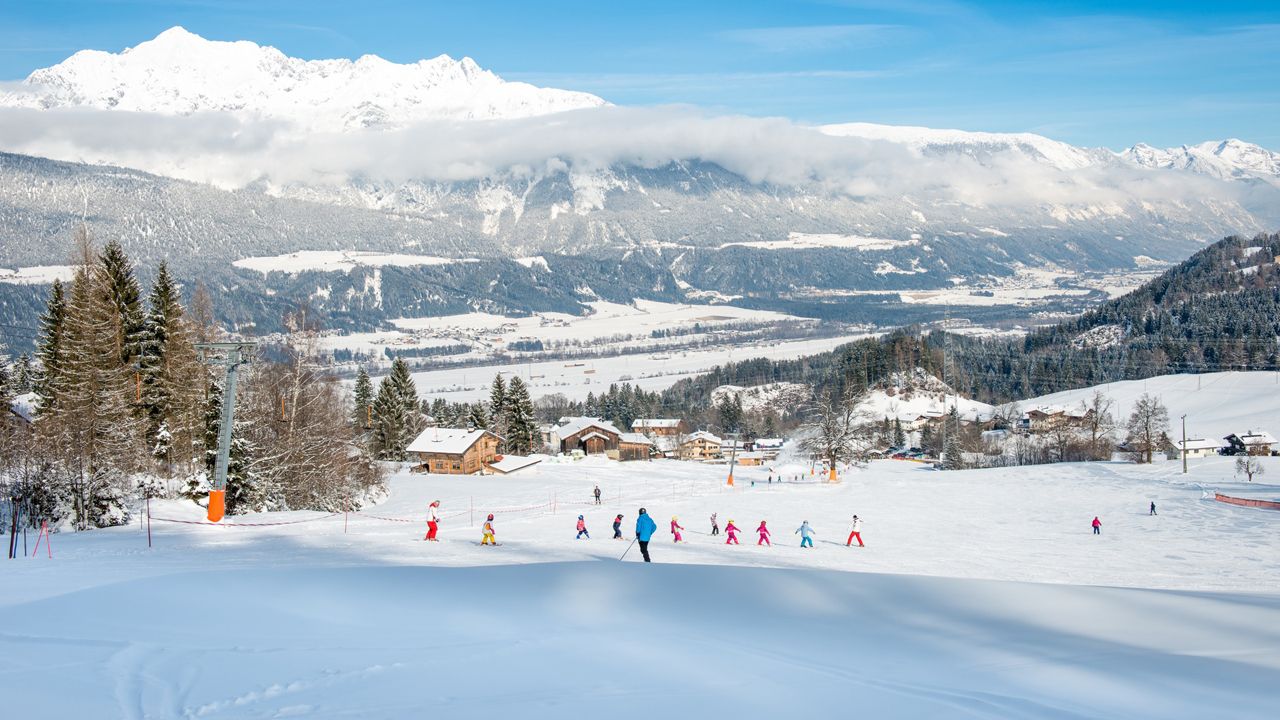 Burglift – Stans in Austria - a group of people skiing down a snowy slope.