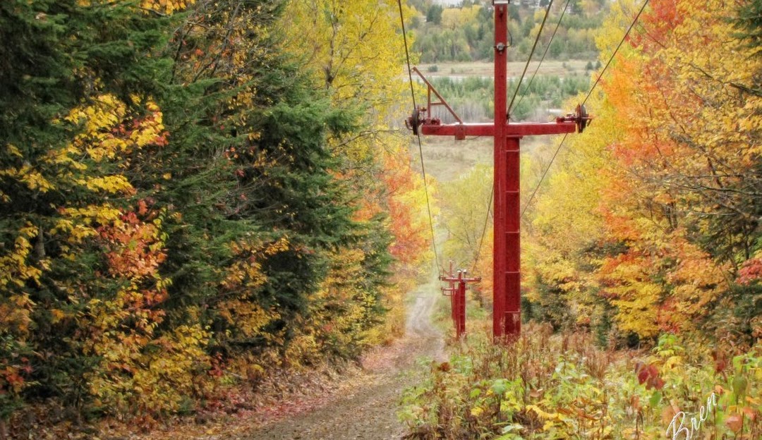 Ski lift ascending Mont Farlagne in Canada with a charming chalet nestled at the base. The ski resort is bustling with winter sports enthusiasts.