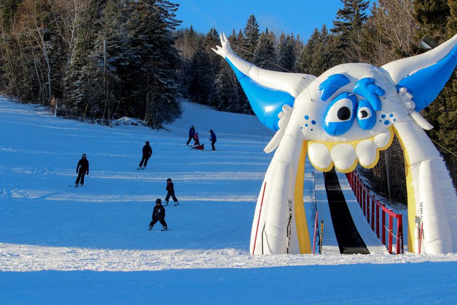 Winter sports enthusiasts enjoying a day at Mont Farlagne ski resort in Saint-Jacques, New Brunswick, Canada, with a charming chalet in the backdrop.