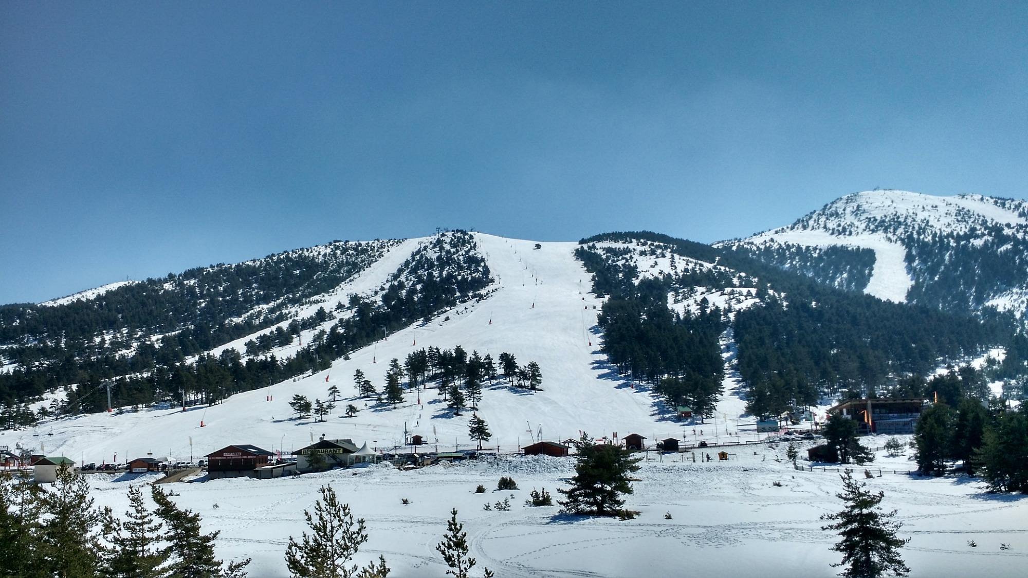 A picturesque view of the ski resort at Gréolières Les Neiges featuring a charming chalet and pristine snow-covered mountain slopes offering an idyllic setting for winter sports.