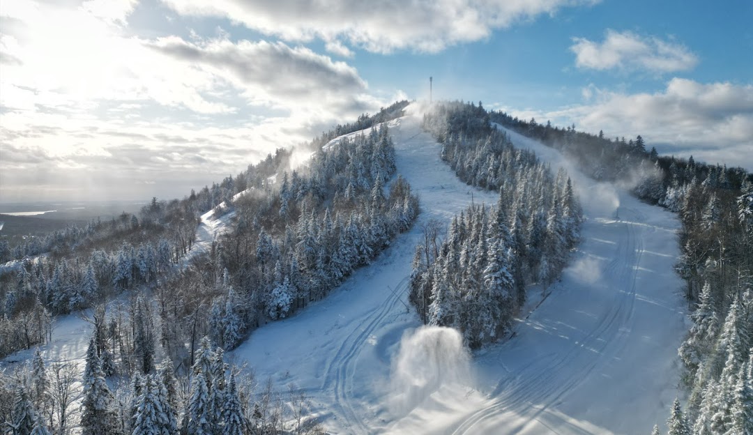 Winter scene at Mont Adstock ski resort in Quebec, featuring a ski lift and a skier enjoying the snow-covered slopes amidst a picturesque backdrop.