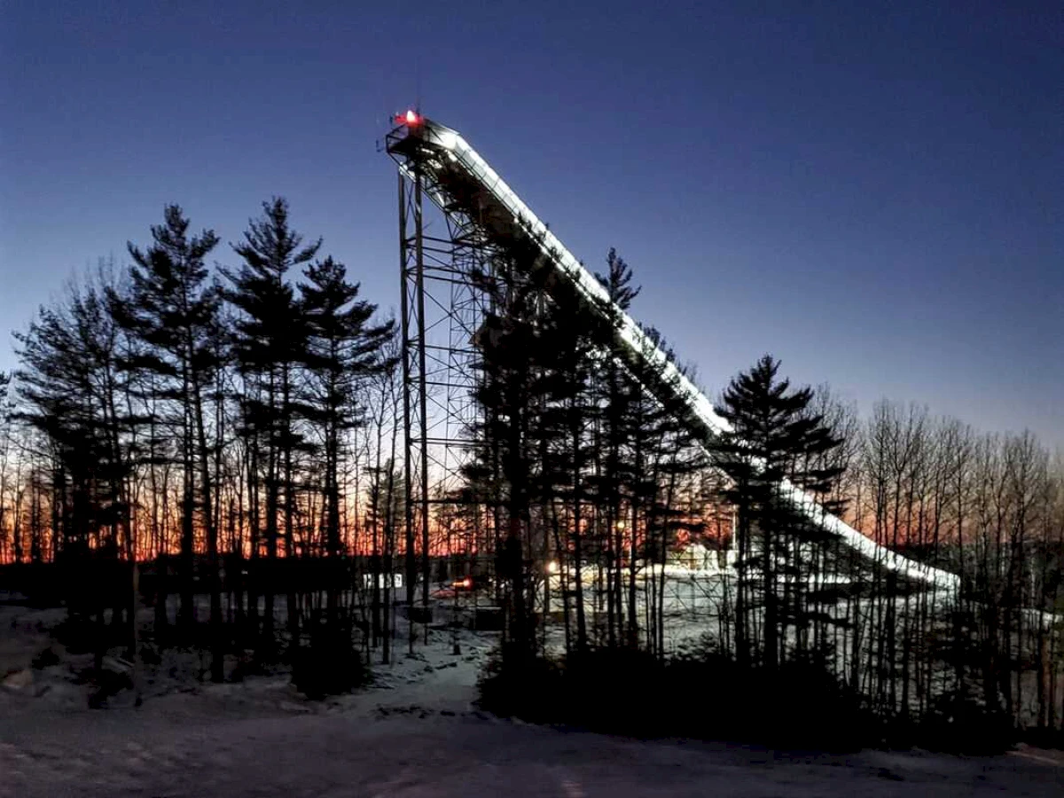 Winter sports enthusiasts enjoying the snowy slopes of Pine Mountain in Iron Mountain, Michigan, facilitated by a ski lift operating in a picturesque ski resort enveloped by stunning winter scenery.