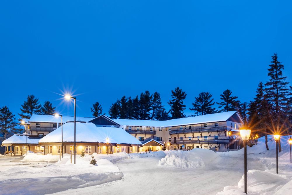 View of Pine Mountain ski resort in Iron Mountain, Michigan, showcasing a bustling winter sports scene, prominent lodge, and stunning snowy landscape.