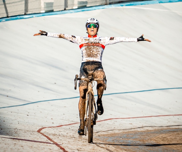 A mountain biker exploring the picturesque landscape of Ala di Stura in Torino, Italy. A chalet can be seen in the backdrop amidst snowy mountains.