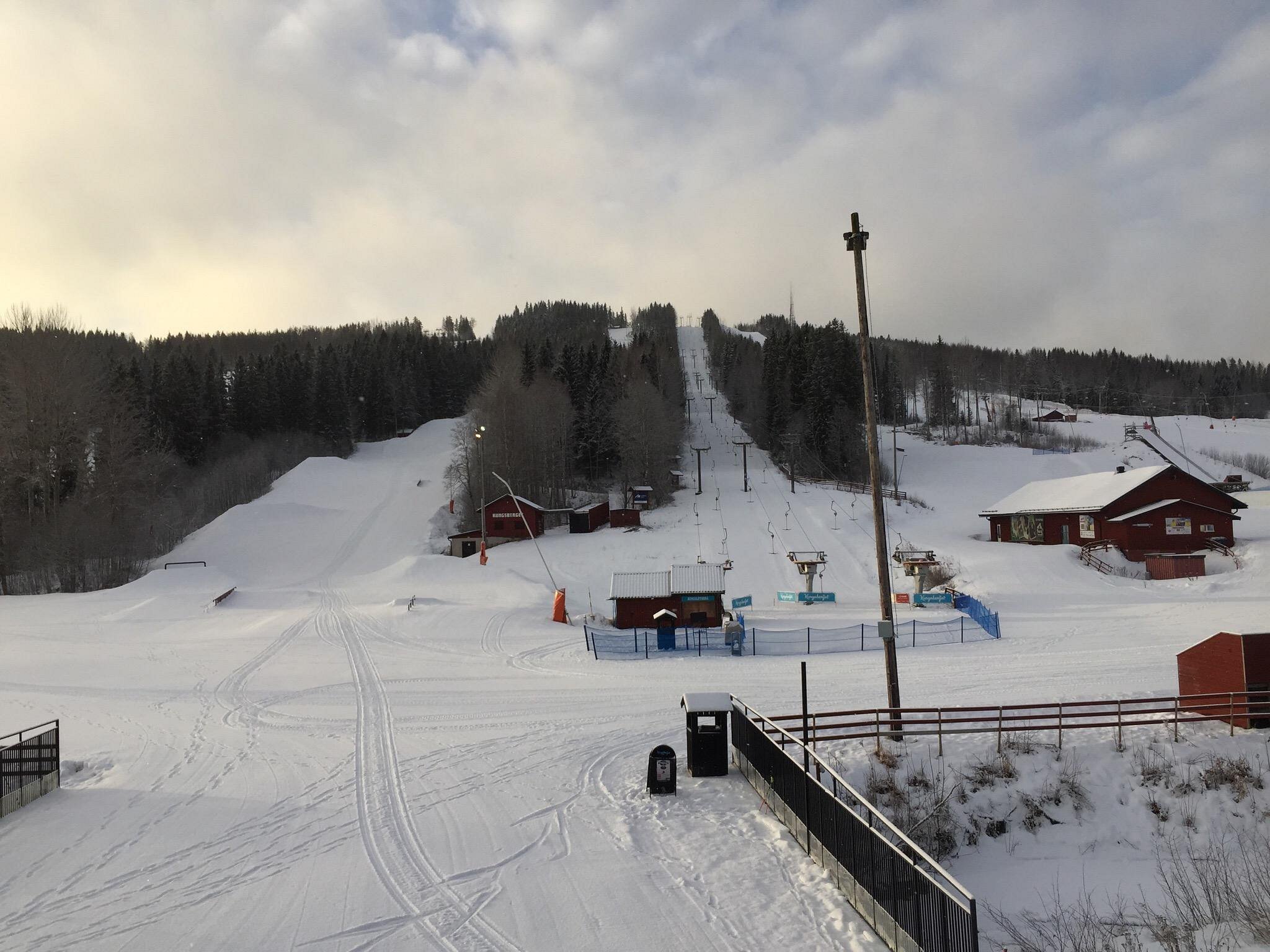 Winter scene at Kungsberget ski resort in Järbo, Sweden, featuring active skiers, a ski lift, and a stunning snowy landscape.