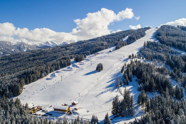 Ski resort in Fageralm - Forstau, Austria with a charming challet, ski lift, and enthusiasts enjoying winter sports amid captivating winter scenery.