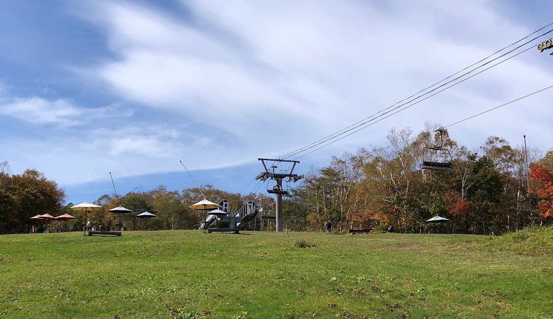 View of Spring Valley Izumi Kogen Sendai in Japan featuring a prominent ski lift threading through the peaceful, snow-dusted pistes of the ski resort with a charming chalet peeking in the background.