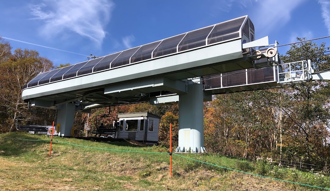 View of a charming chalet and a cozy lodge at Spring Valley Izumi Kogen Sendai on a sunny day in Japan. Enjoy the ski lift service and explore the snowy terrain with a snowmobile.
