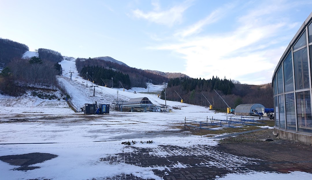 Winter scene at Spring Valley Izumi Kogen Sendai, Japan, showcasing a bustling ski resort with skiers enjoying the slopes, complemented by a stunning snowy landscape and a ski lift in the distance.
