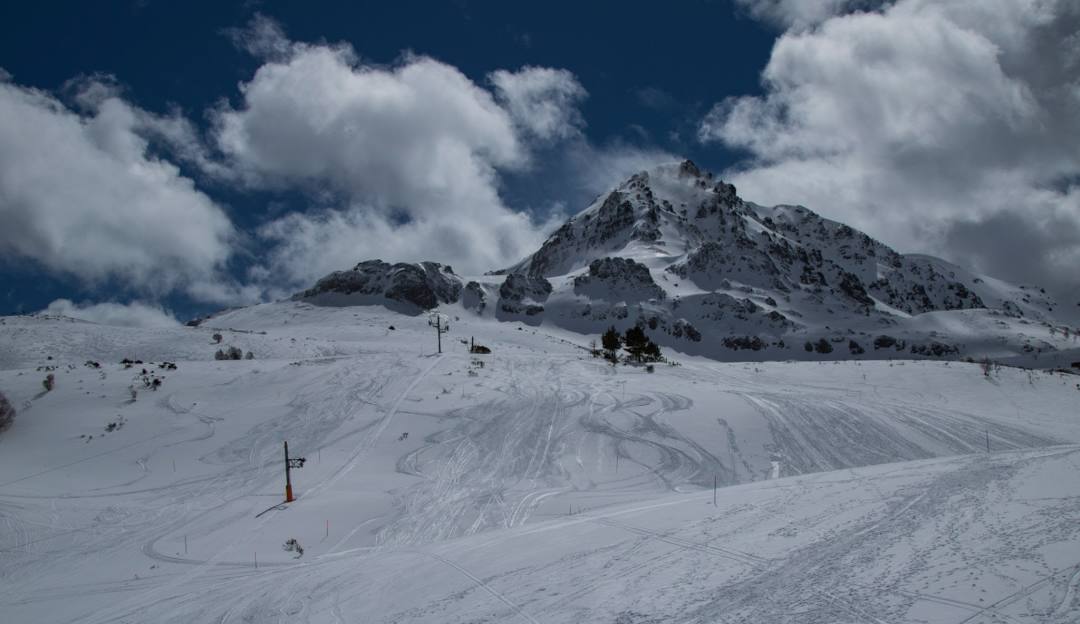 View of Fuentes de Invierno in Spain showcasing a chalet of a ski resort during winter with ski lifts and skiers in action.