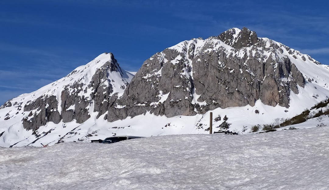 View of the snowy mountains at Fuentes de Invierno in Asturias, Spain, featuring a chalet and a mountain hut. Active winter sports are taking place in the distance.