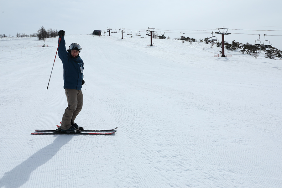 A skier and a snowboarder are enjoying winter sports amidst a magnificent snowy landscape at Shirakabako Royal Hill in Japan. Nearby a charming chalet and a ski lift add to the idyllic winter scene.
