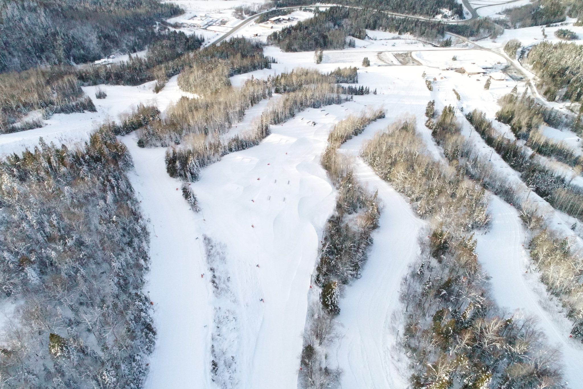 A picturesque view at Sugarloaf Provincial Park New Brunswick showcasing a functional ski resort on a winter's day with a skier gliding down the snow-covered slope captured against a backdrop of a ski lift.