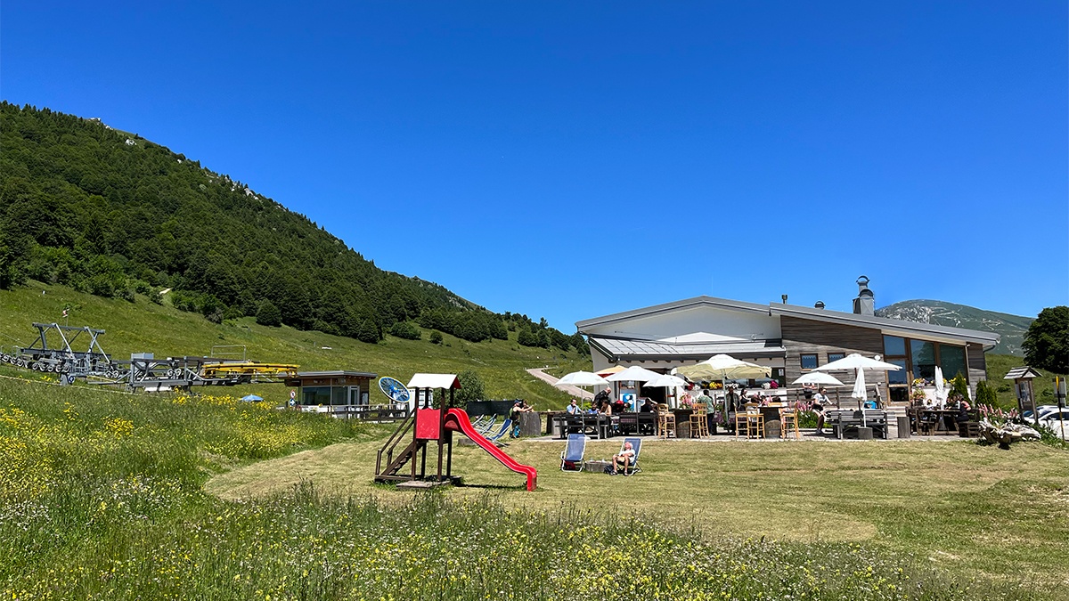 Prà Alpesina Chairlift - Upper terminal in Italy - a group of people standing in a field.