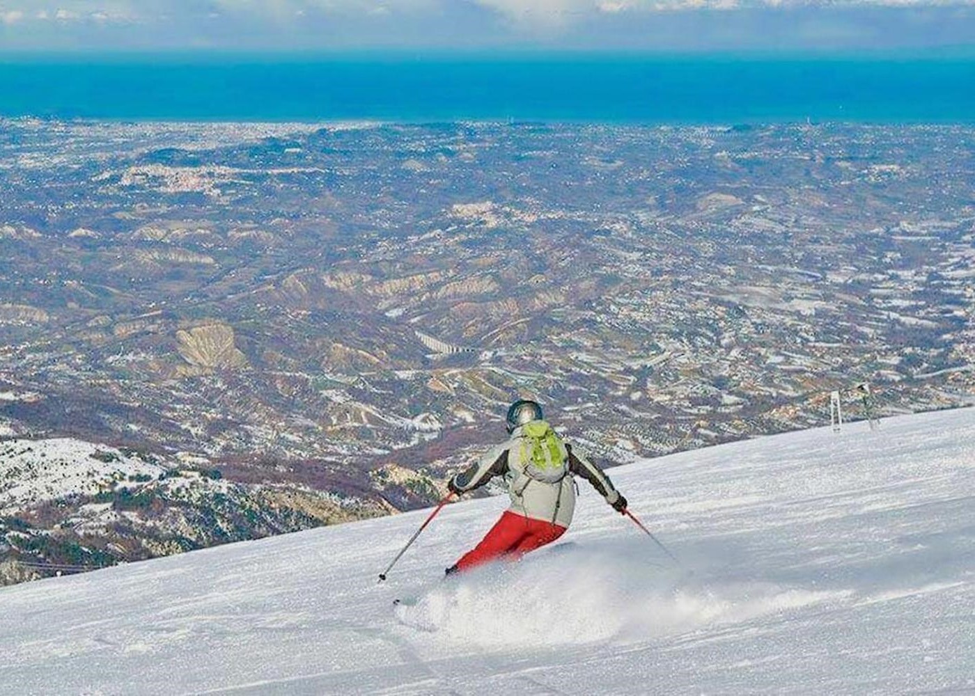 Etna Sud, Nicolosi in Italy - a person skiing down a snowy slope in the mountains.