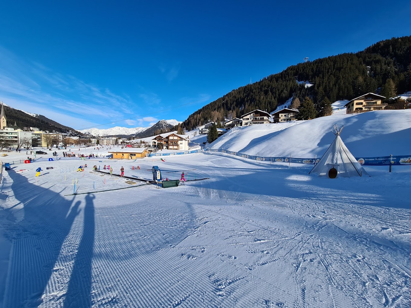 Winter sports enthusiasts enjoy Jakobshorn ski resort in Graubünden, Eastern Switzerland, with a challet and stunning alpine scenery in the backdrop.