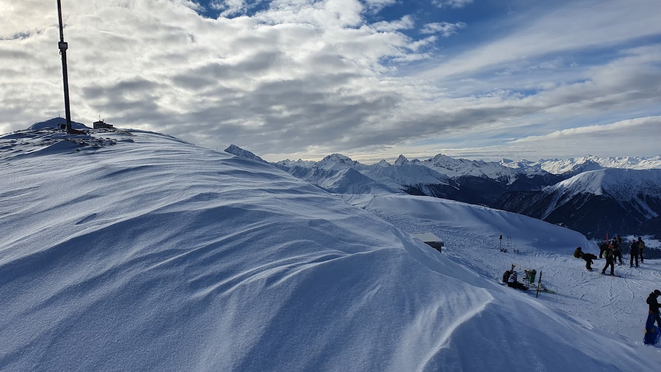 A winter sports scene at Jakobshorn in Graubünden Eastern Switzerland featuring a charming chalet against a backdrop of majestic snowy mountains. The landscape is blanketed in snow painting a serene winter scenery.