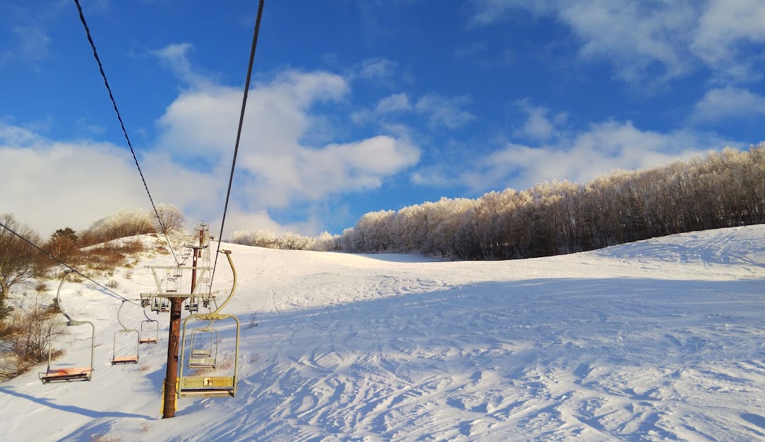 Ski resort at Yamaboku - Yamada Bokujo in Japan, featuring a ski lift against a stunning winter landscape, complete with a charming chalet.