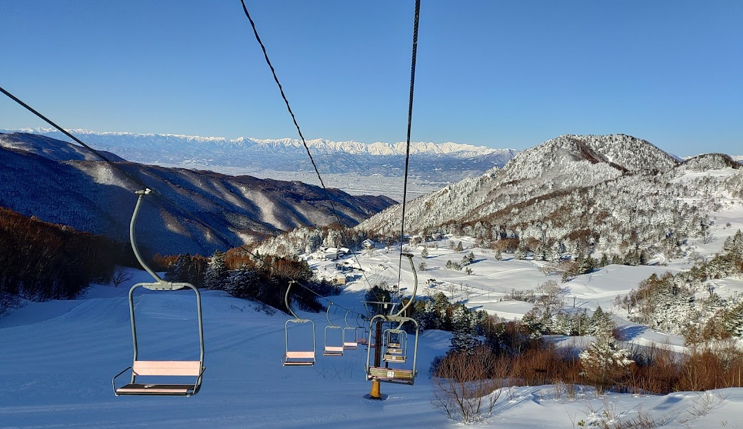 View of the picturesque Yamaboku ski resort in Okuyamada, Japan featuring a ski lift, a charming chalet, and inviting winter sports scene amidst a stunning landscape blanketed in snow.