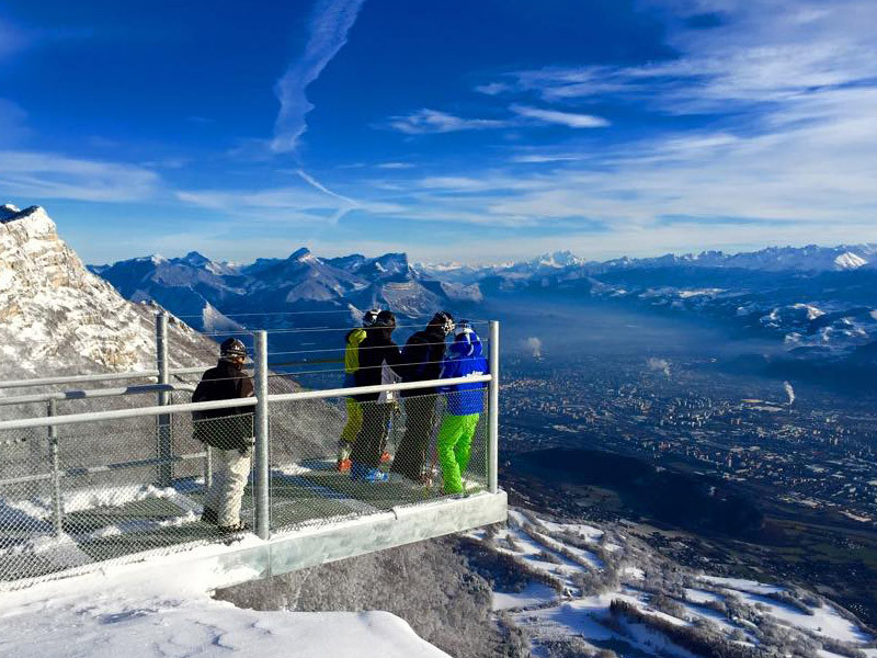 A scenic winter view in Lans en Vercors France featuring a chalet and a mountain backdrop. A family is enjoying skiing at the local ski resort.