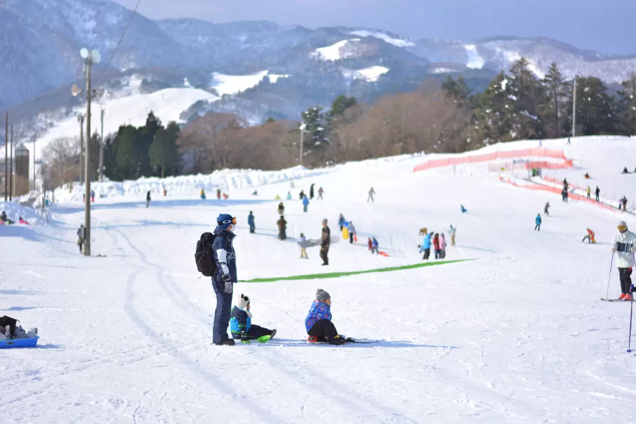 Manba in Japan - a group of people skiing down a snowy hill.