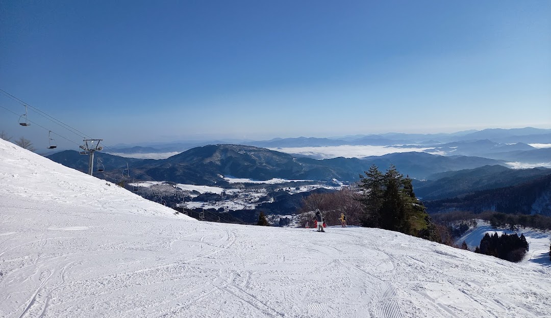 A bustling winter sports scene at the Manba ski resort in Kansai, Japan featuring a charming chalet and a skier gliding through magnificent winter scenery.