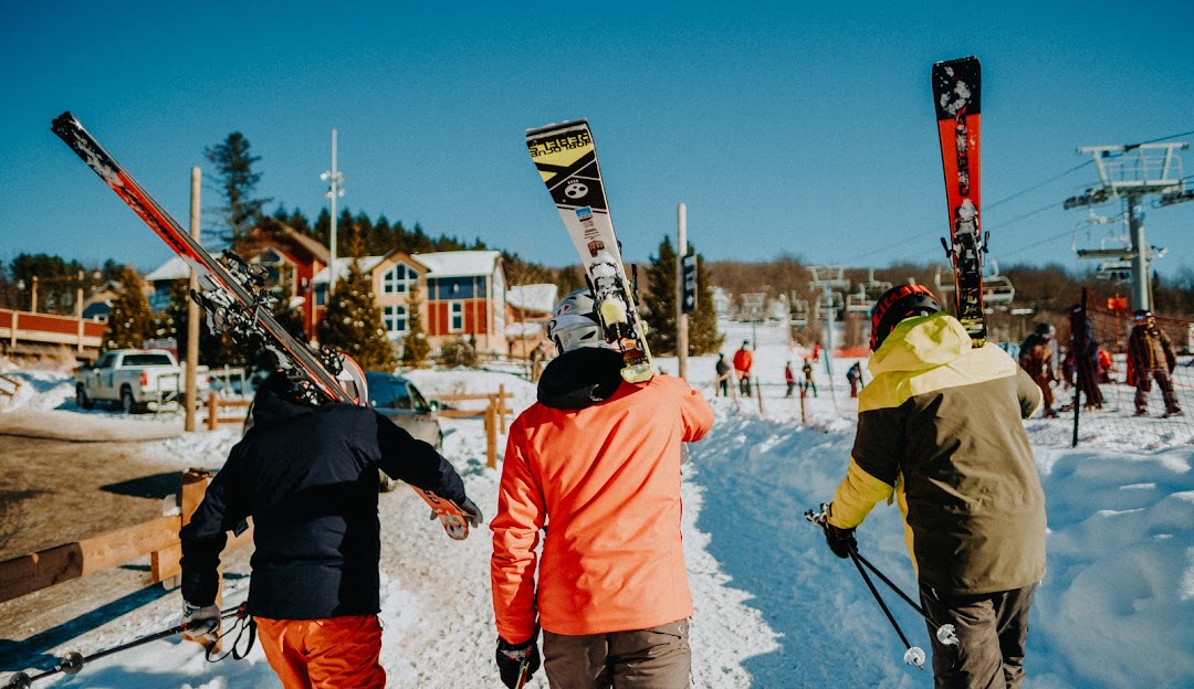 Winter sports enthusiasts enjoying a day of family skiing at Mont Gleason ski resort in Tingwick, Quebec, Canada, with visible ski lifts and skiers dotting the snowy landscape.