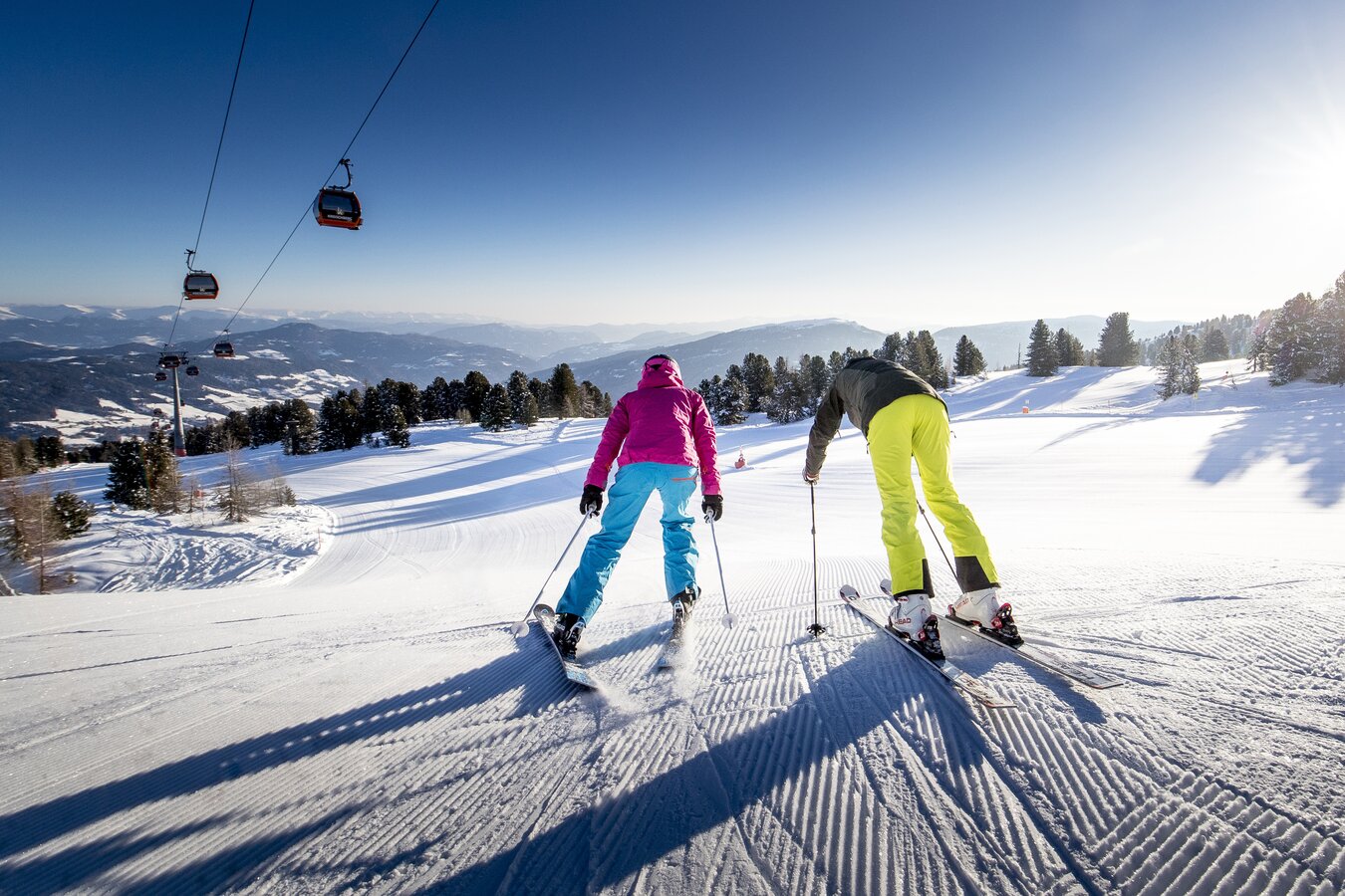 Kreischberg in Austria - two people skiing down a slope on a sunny day.