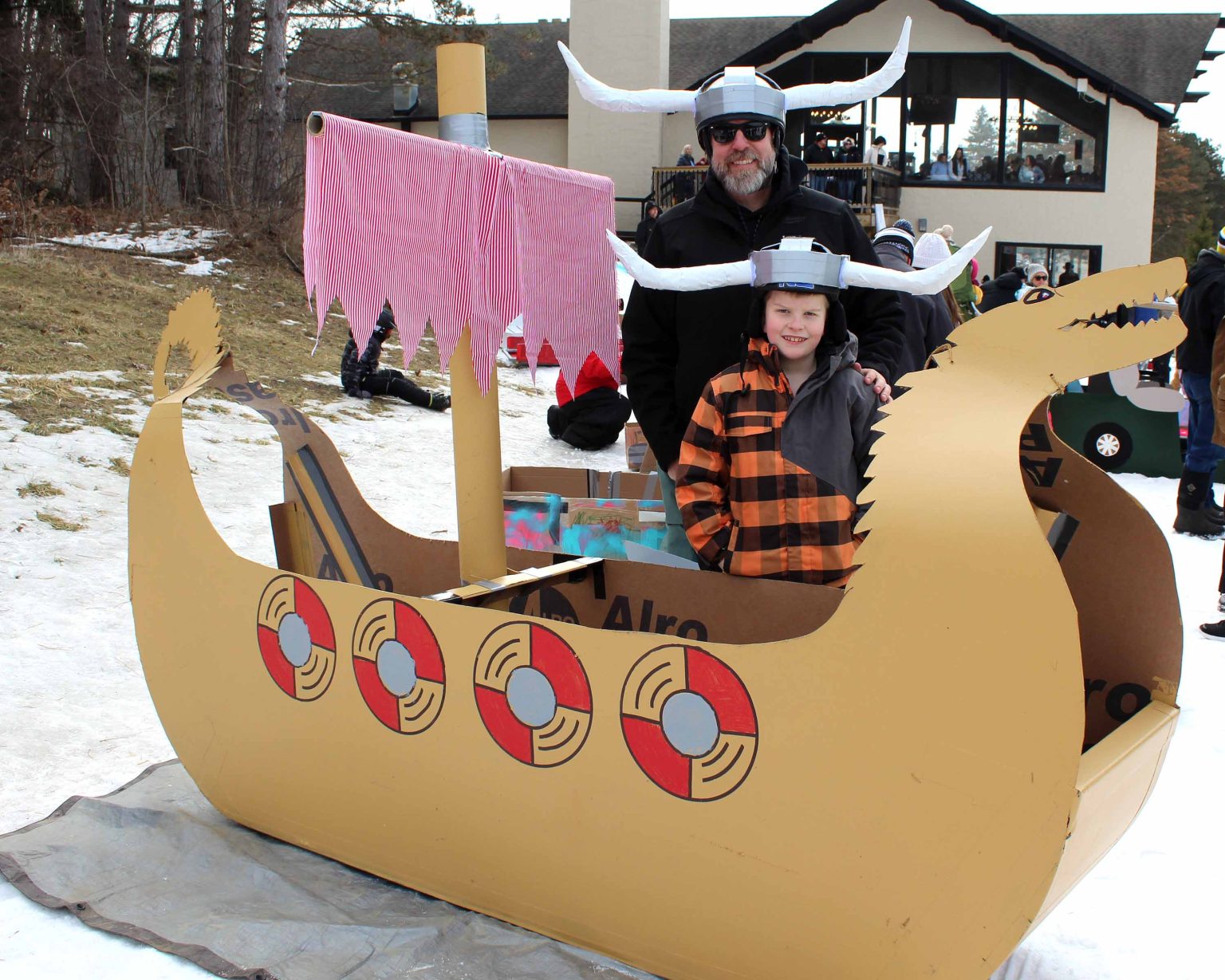 Alpine Mountain Ski & Snow Tubing Center in USA - a man and a little boy in a cardboard boat.