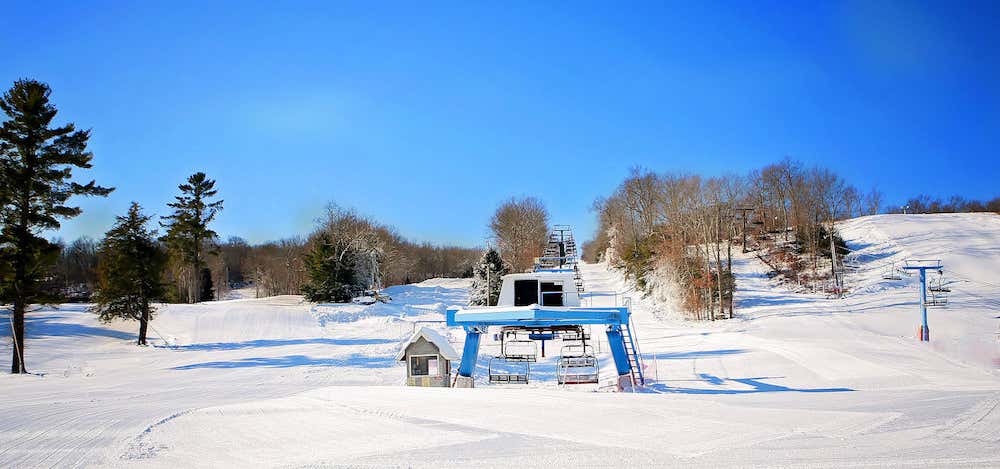 Alpine Mountain Ski & Snow Tubing Center in USA - a snow covered ski slope with trees in the background.