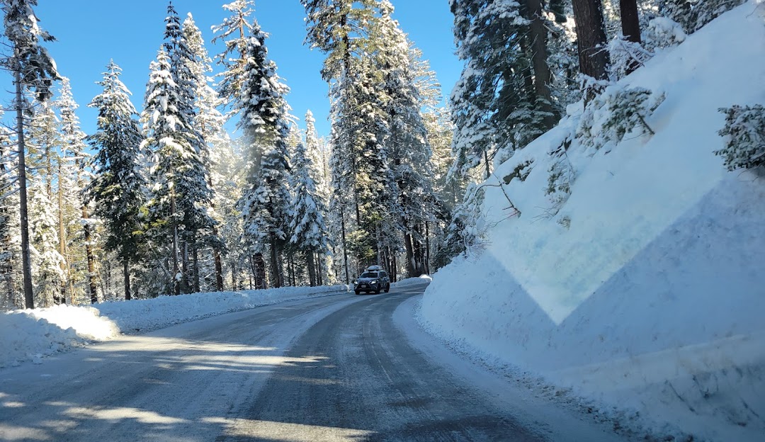 A breathtaking winter scene at Badger Pass in Yosemite National Park, California. The landscape is cloaked in pristine snow, featuring spots for winter sports, and a snowmobile on the foreground.