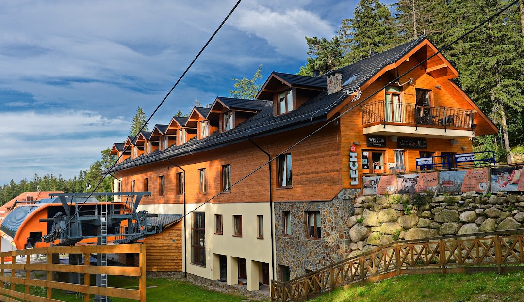 View of the Winterpol White Jar Lodge in Karpacz Poland set in a scenic ski resort with a winter sports centre featuring chalets and a mountain hut.
