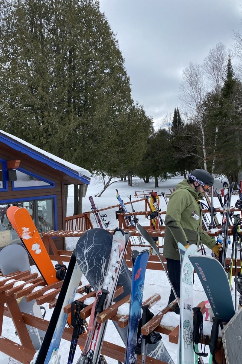 Otsego in USA - a group of people standing around a pile of snowboards.