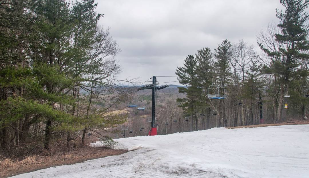 A picture from Mohawk Mountain showcasing a ski lift against a winter sports backdrop with a skier heading down snow-covered slopes at a ski resort in Cornwall Connecticut USA.