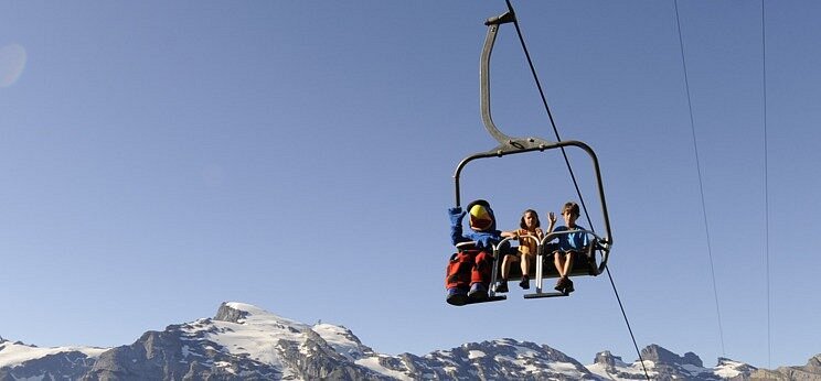 A picturesque scene at Brunni-Bahnen ski resort in Engelberg Switzerland showcasing a ski lift resort chalet and families enjoying winter sports.