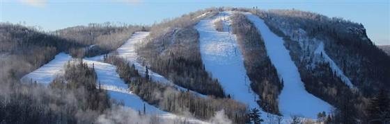 Breathtaking view of Loch Lomond ski resort in Thunder Bay, Ontario, showcasing a buzzing winter sports scene. The picture includes a busy ski lift transporting participants, a cozy challet, and mesmerizing snow-covered slopes.