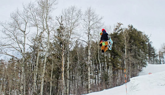 A snowboarder setting off on a thrilling ride at the snowy Loch Lomond hills in Thunder Bay, Ontario, Canada. The pristine white snow under clear skies provides an ideal setting for winter sports.