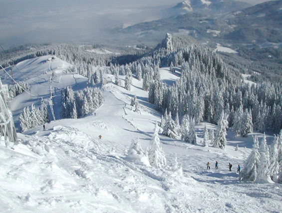 View of the bustling Grüntenlifte – Kranzegg ski resort in Bavaria Germany. Scene shows skiers enjoying the snow-covered slopes with a ski lift in the background.