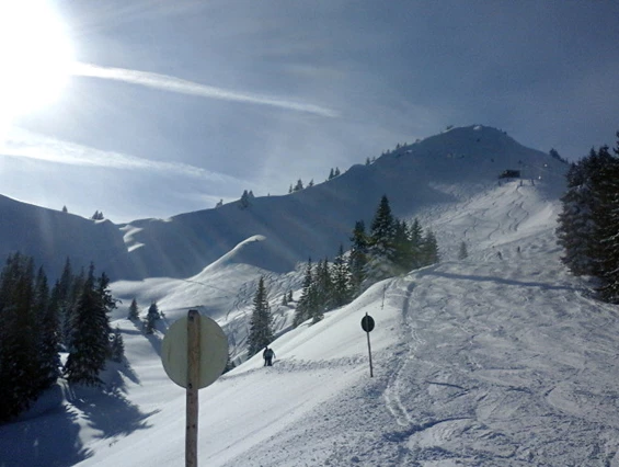A winter scene at Grüntenlifte – Kranzegg ski resort in Bavaria, Germany, showcasing a charming challet amidst skiers and a ski lift.