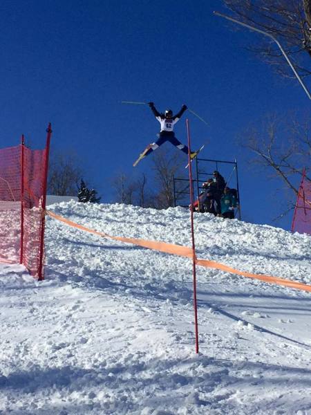 A skier and a snowboarder enjoy a winter sports scene amidst heavy snowfall in Colden, New York. A chalet and a winter sports centre add to the charming landscape.