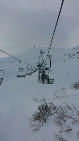 A picturesque view of Cerreto Laghi monte La Nuda in Italy featuring a ski lift and resort nestled amid snow-covered slopes presenting a vibrant winter sports scene.