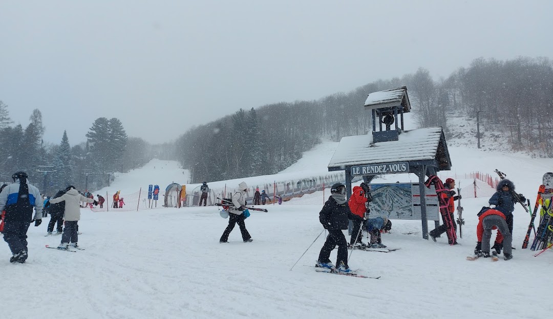 Winter sports scene at Montcalm Ski Resort in Rawdon Quebec featuring an active skier descending the snow-covered slopes. A quaint chalet and a ski lift dot the landscape adding charm to the wintry Canadian vista.