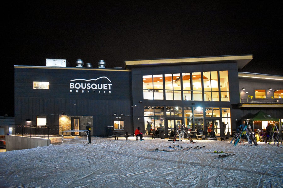 Winter view of Bousquet Ski Area in Pittsfield, Massachusetts, featuring a bustling sports center amid a picturesque snowy landscape.