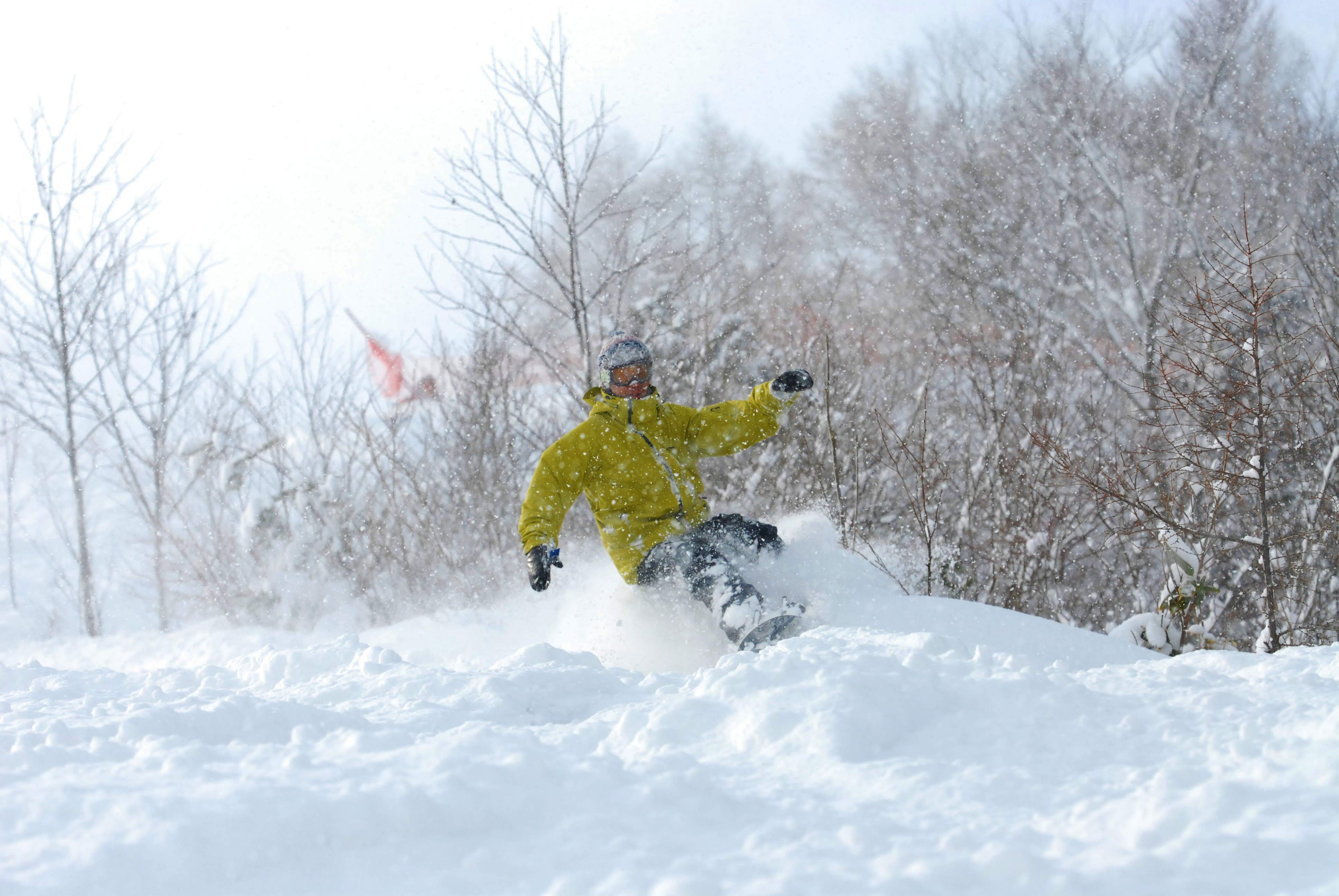 A snowboarder and skier enjoying winter sports in the scenic snow-covered landscape of Hida Kawai, amidst the tranquility of Chūbu, Japan.