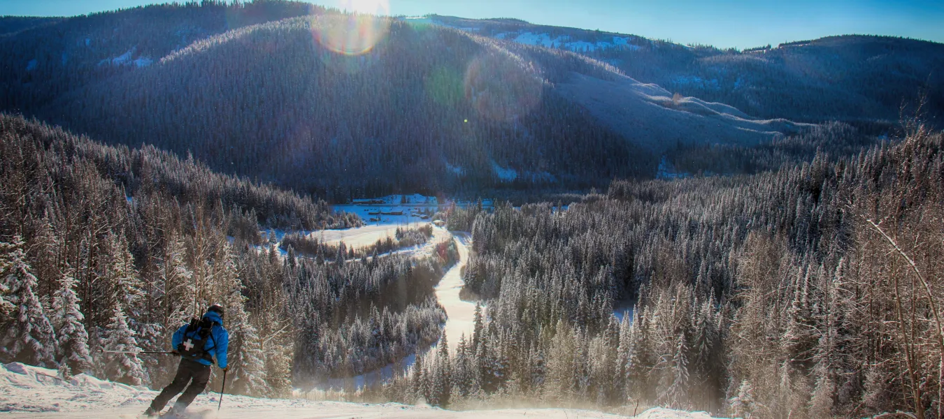 View of the snowy landscape at Troll Ski resort in Quesnel, British Columbia featuring winter sports scenes, a ski chalet, and a winter sports center.