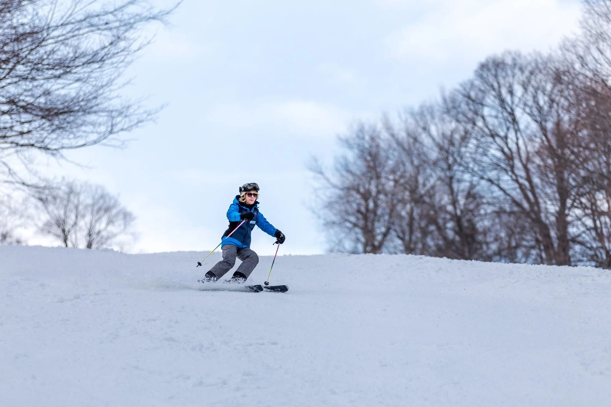 A skier and snowboarder are enjoying winter sports at the Royal Mountain Resort in Johnstown New York. A child is seen learning to ski in the foreground emphasizing the family-friendly atmosphere.
