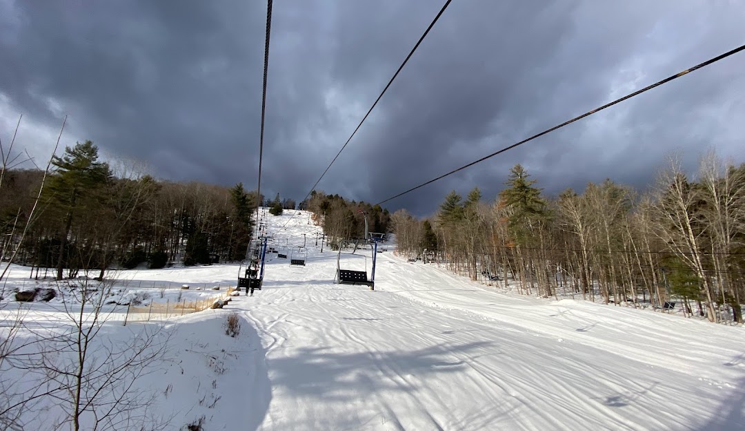Winter sports enthusiasts enjoying the snowy slopes at Royal Mountain ski resort in Johnstown, New York, with a ski lift transporting skiers to the peak amidst the stunning winter scenery.