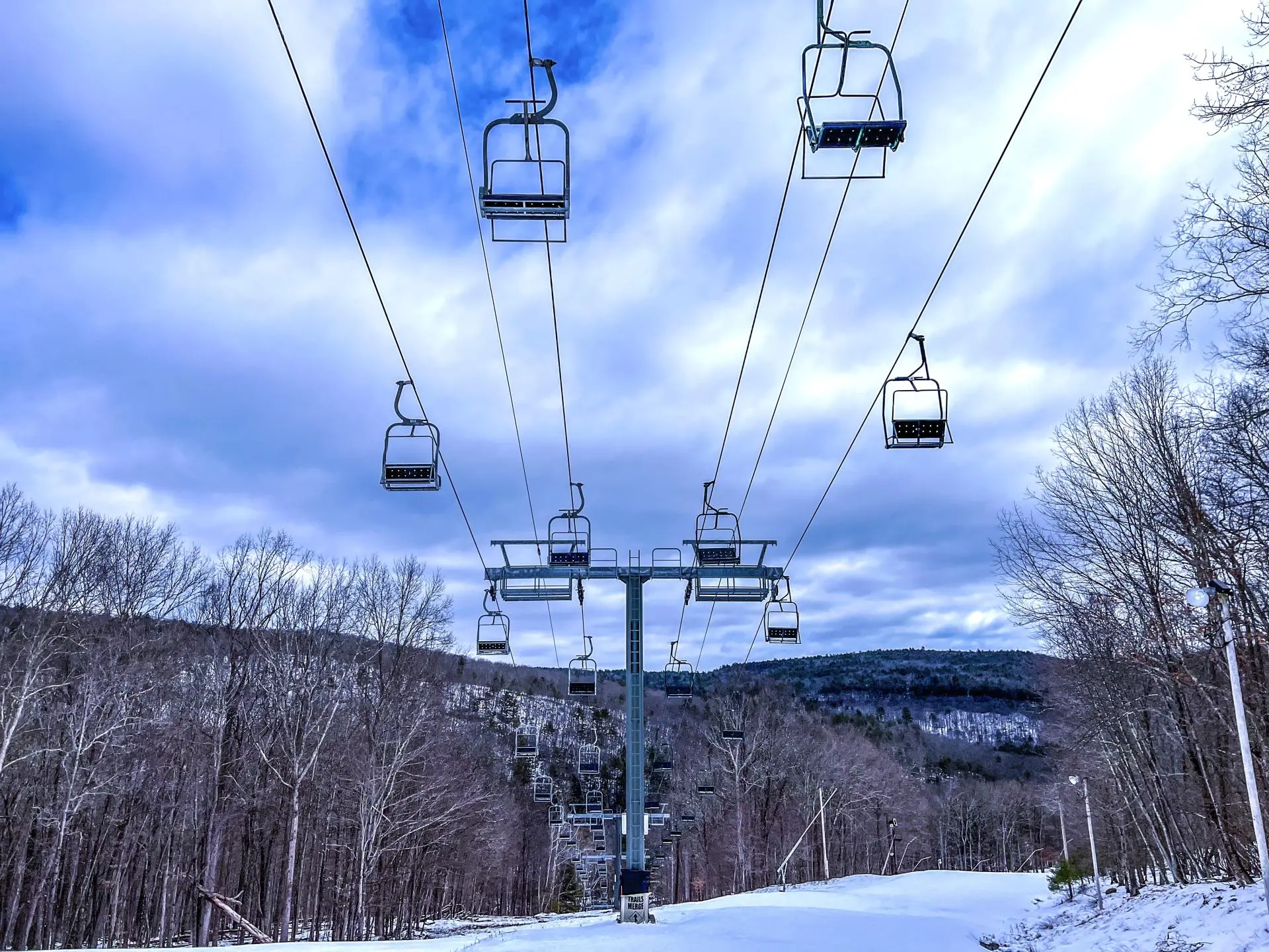View of Big Bear at Masthope Mountain in Pennsylvania, showcasing a ski lift amidst a winter sports scene, ski resort elements in the background, and a challet, all embraced by snow-covered slopes.