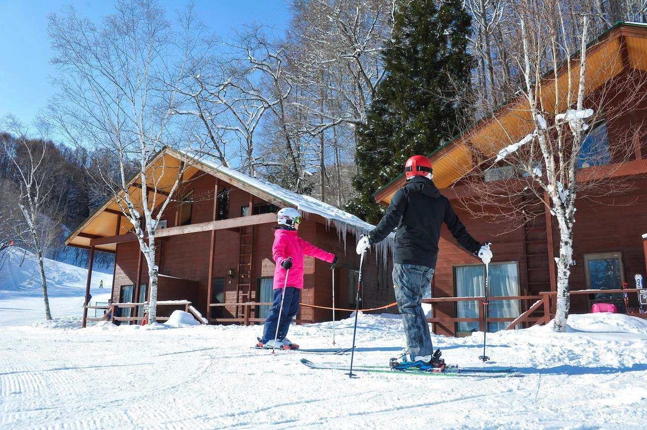Oze Tokura in Japan - two people on ski boards in front of a cabin.